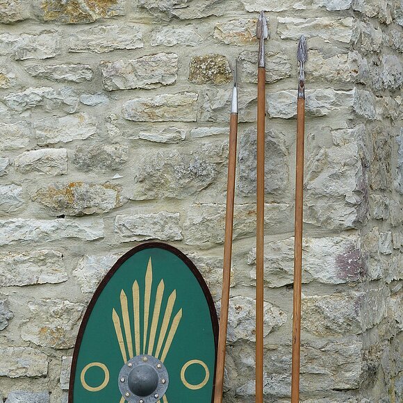 Die Nachbildungen eines römischen Schildes und dreier Pila lehnen an der rekonstruierten Toranlage des Kastell Pfünz. Beim Pilum handelt es sich um einen Wurfspeer, die typische Waffe römischer Legionäre.
