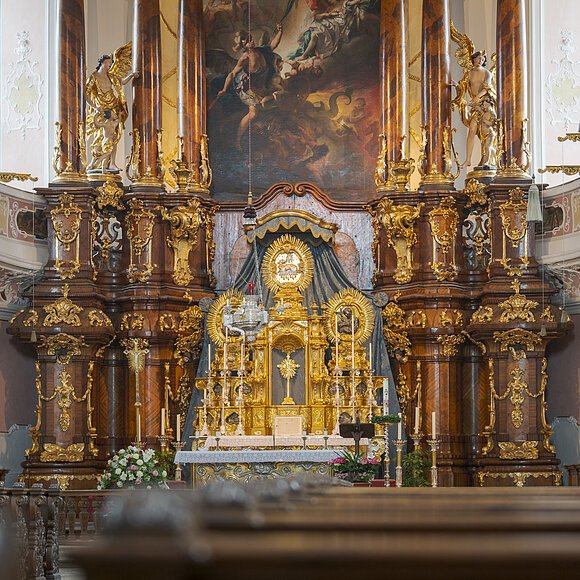 Barocker Kirchenaltar mit reich verzierten goldenen Elementen und Gemälde im Hintergrund.