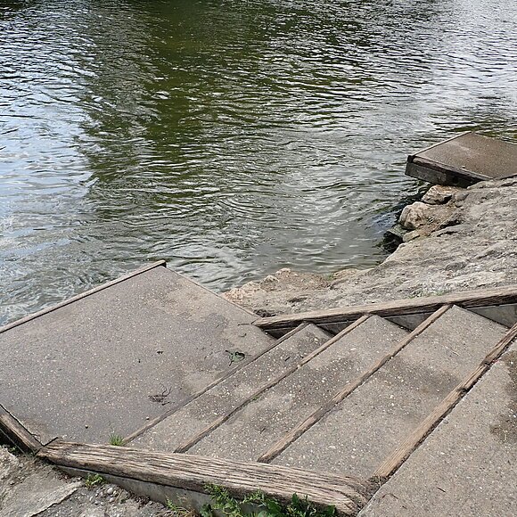 Bootsrastplatz Gungolding Betonstufen mit Holzgeländer führen von einem Ufer zum Wasser eines Flusses oder Sees.